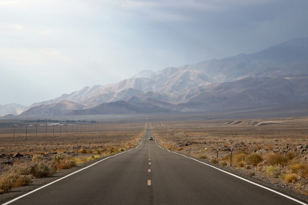 asphalt road going to mountain between grass field