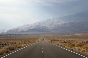asphalt road going to mountain between grass field
